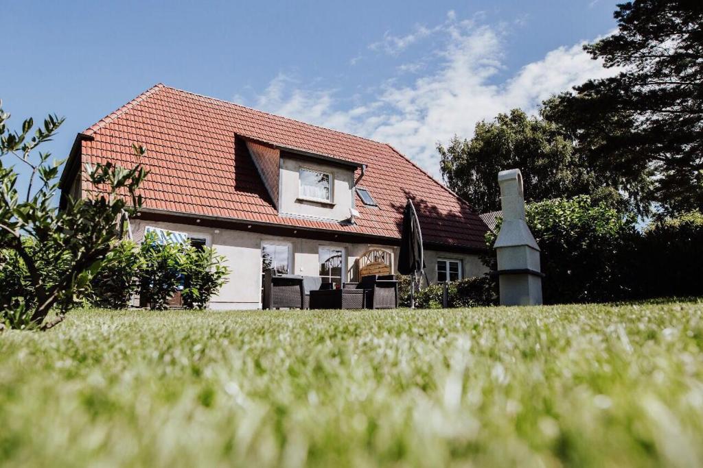 una casa con techo rojo y césped en Landhaus Boldevitz, en Boldevitz