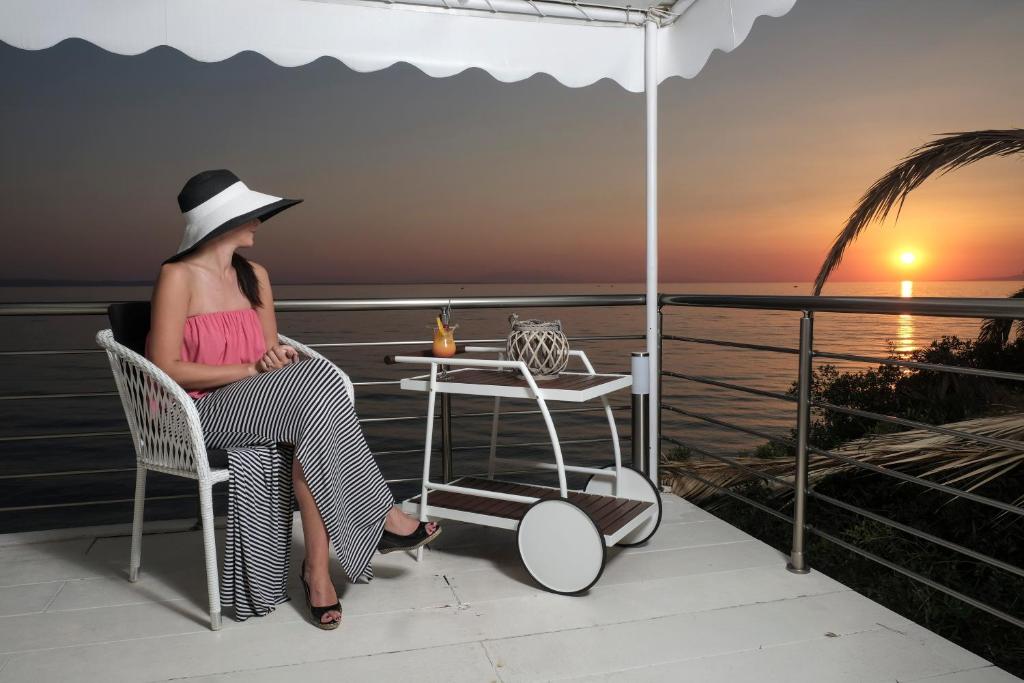 a woman sitting on a balcony watching the sunset at Acrotel Athena Villa in Elia