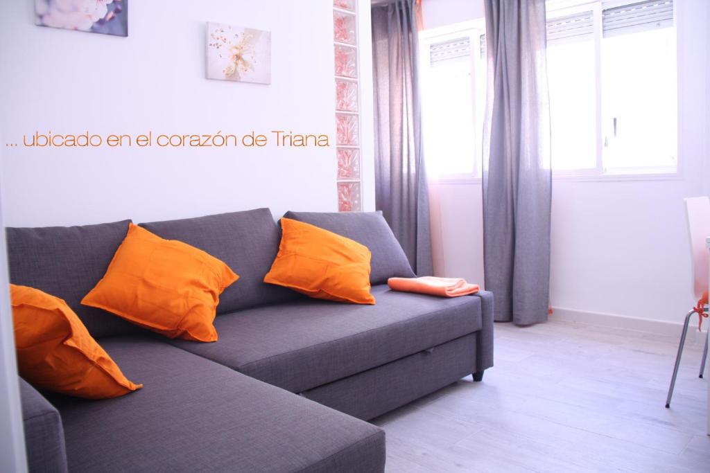un sofá azul con almohadas naranjas en la sala de estar. en Apartamento Orange Triana centro, en Sevilla