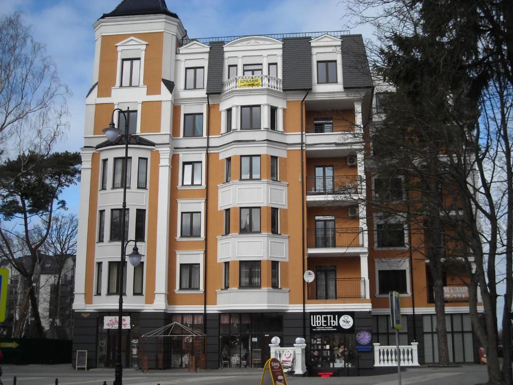 スヴェトロゴルスクにあるApartment Гармония Alt Plats 1の通り沿いの高いオレンジと白の建物