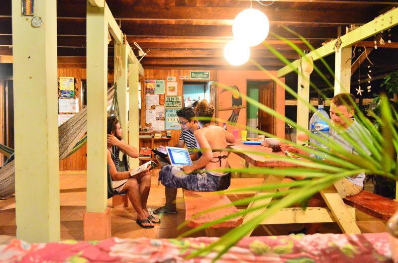 a group of people sitting around a table with a laptop at Hostel Mariposas in Sámara