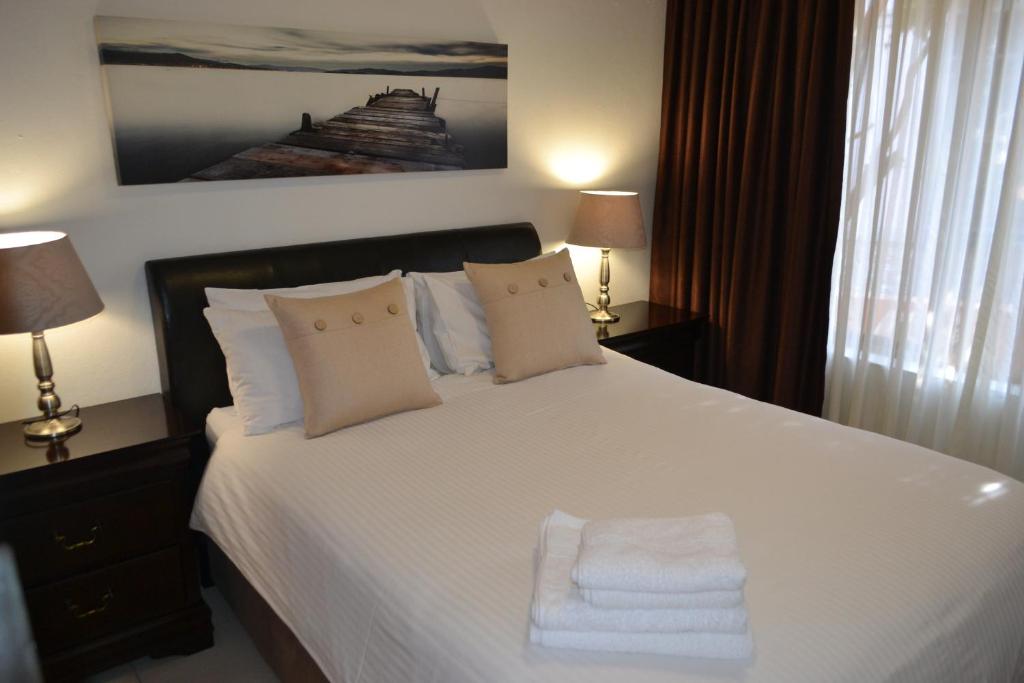 una camera da letto con un letto bianco con due asciugamani di Alendo Apartments a Johannesburg
