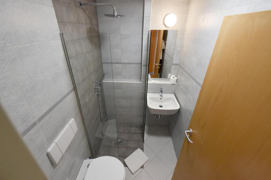 a bathroom with a shower and a toilet and a sink at Hotel Korotan in Vienna