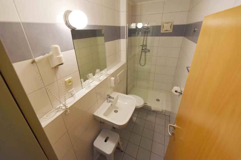 a bathroom with a sink and a toilet and a mirror at Hotel Korotan in Vienna