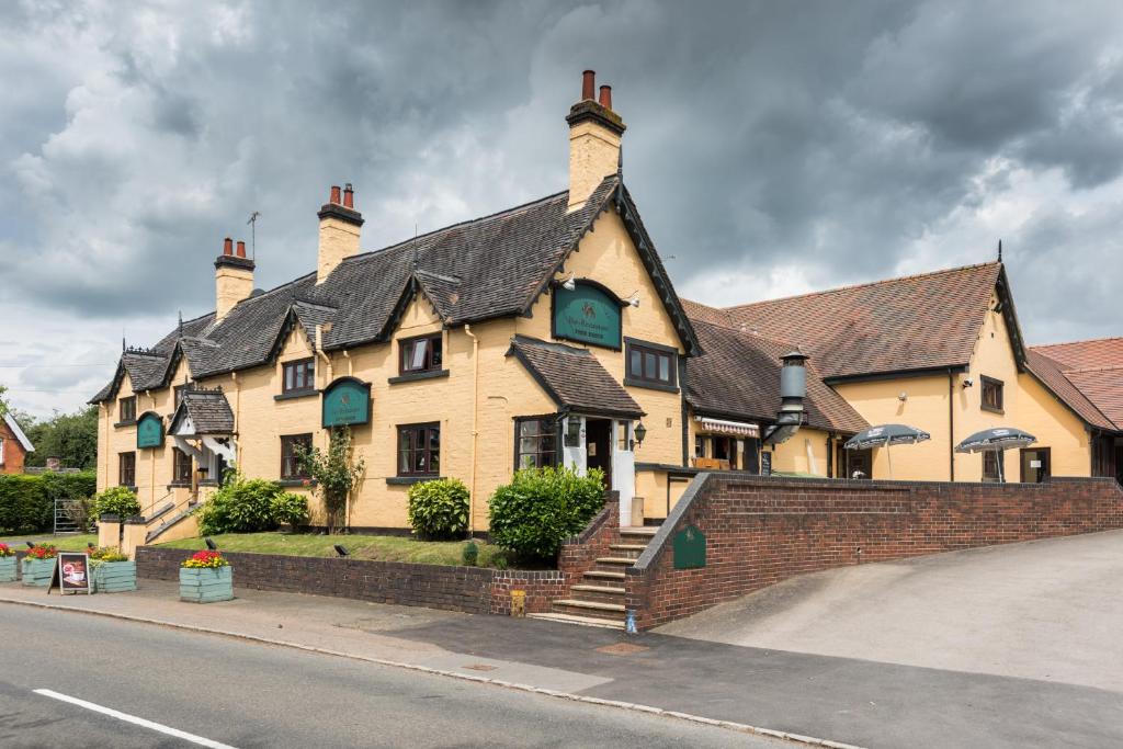 a large yellow building with a black roof at Golden Lion Hotel in Rugby