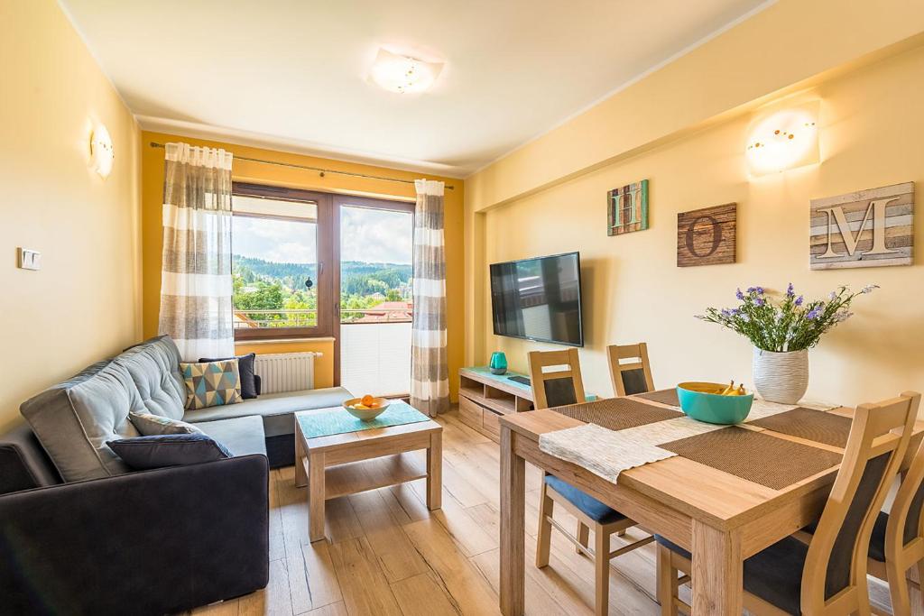 a living room with a dining room table and a couch at Apartament Sweet Home in Krynica Zdrój