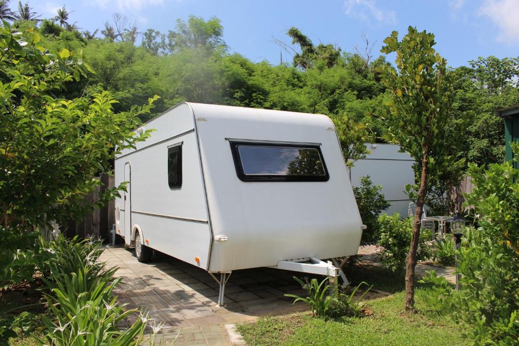 uma caravana branca estacionada num jardim em Kenting Houbihu Camping Car B&B em Hengchun South Gate