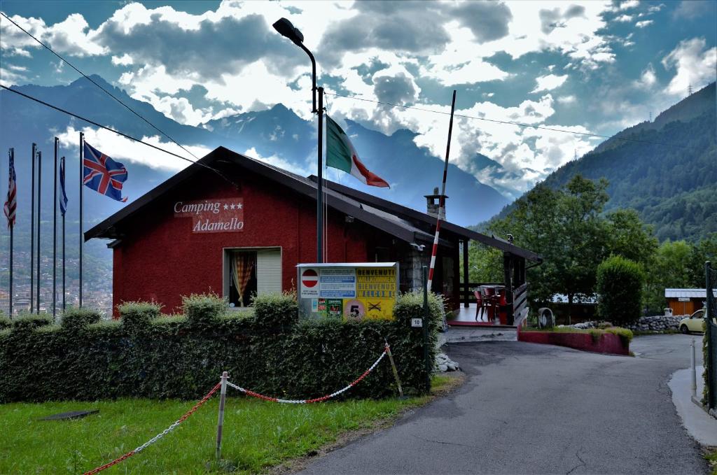 un edificio rojo con dos banderas encima en Camping Adamello, en Edolo