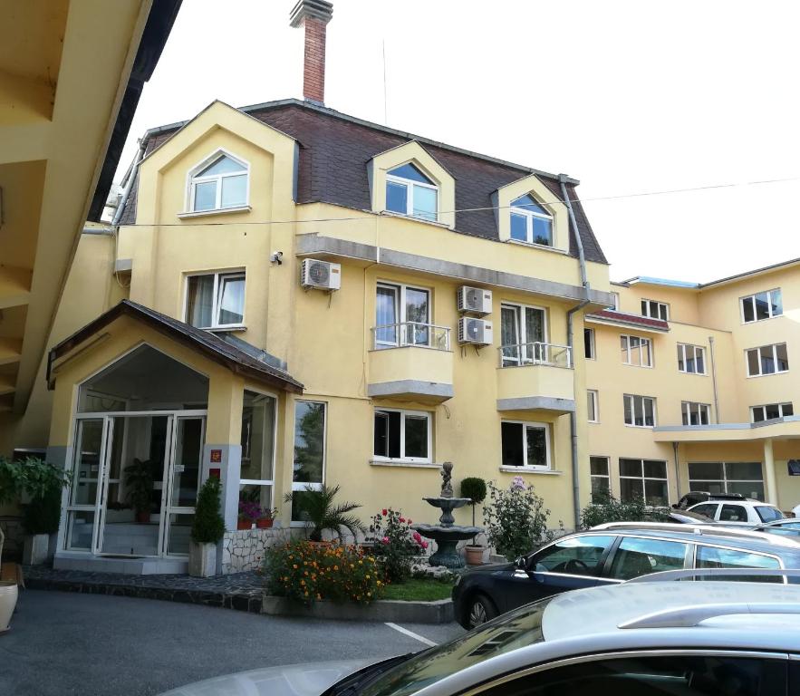 a yellow building with cars parked in front of it at Hotel Galant in Sofia
