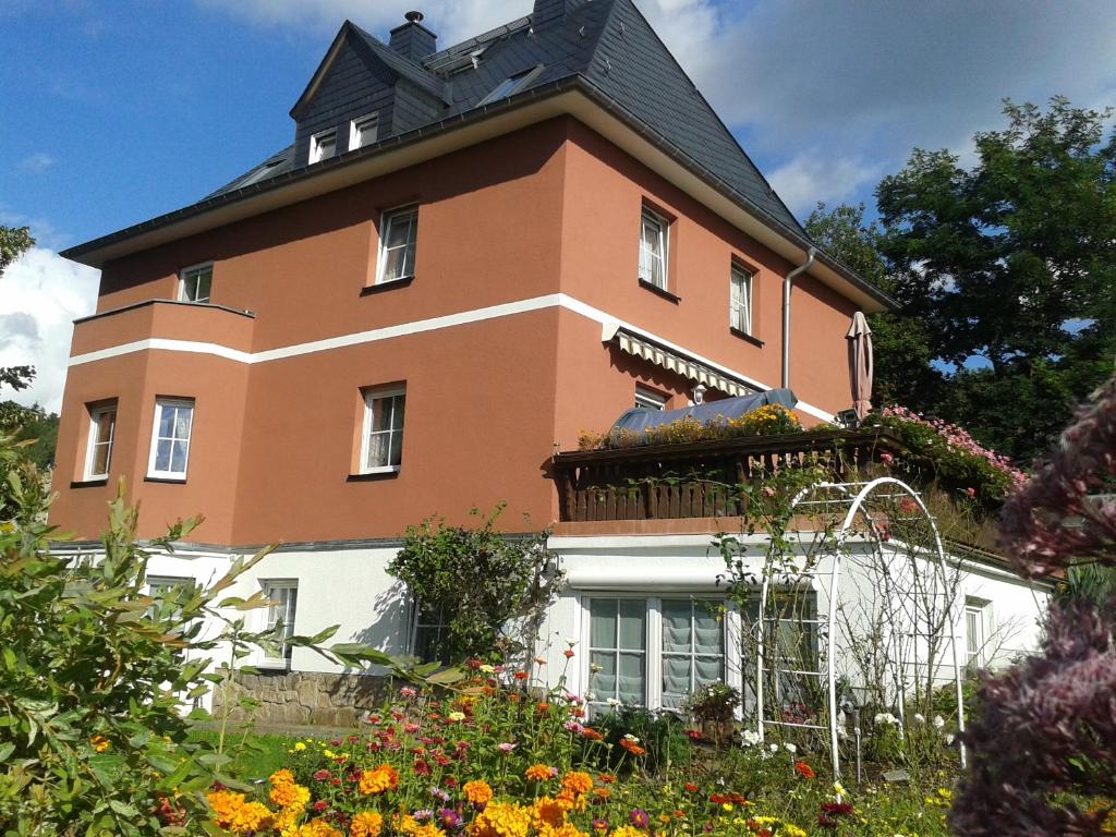 ein großes Backsteingebäude mit einem Balkon im Garten in der Unterkunft Pension Irmisch in Aue