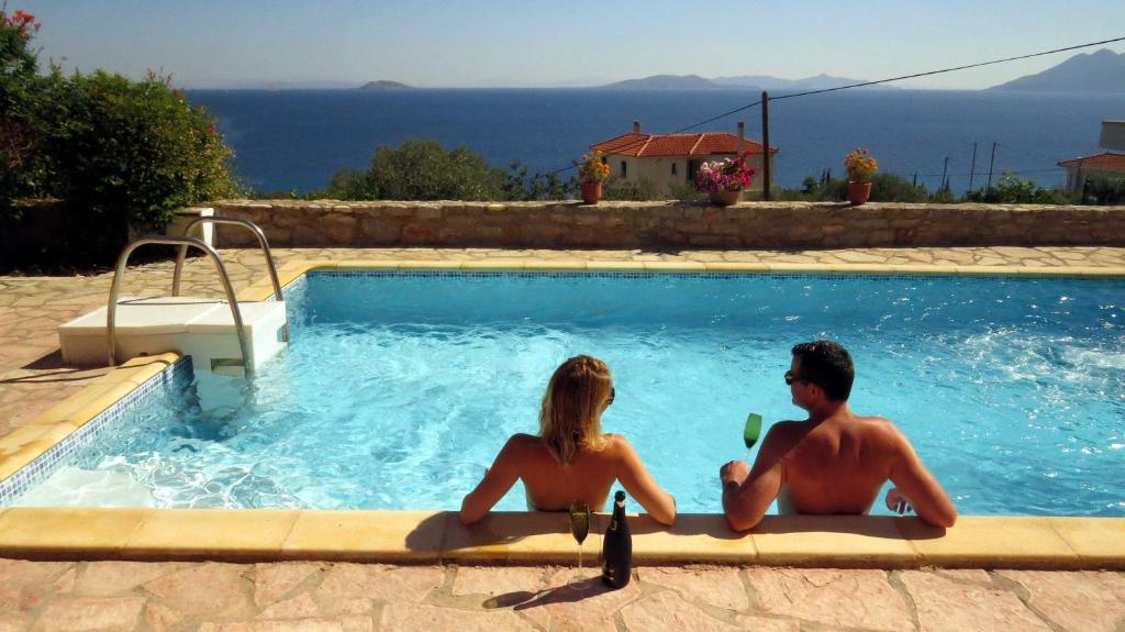 a man and woman sitting in a swimming pool at Villa Irini in Ancient Epidauros