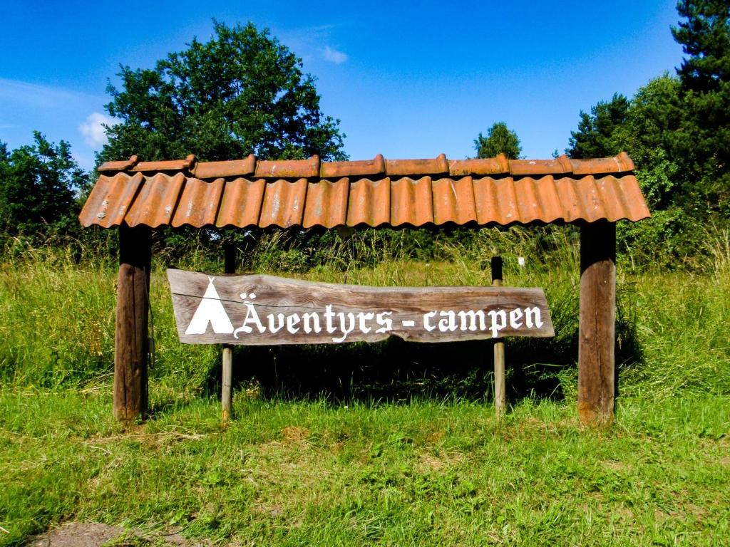 un panneau dans un champ avec toit dans l'établissement Äventyrscampen, à Sjöbo