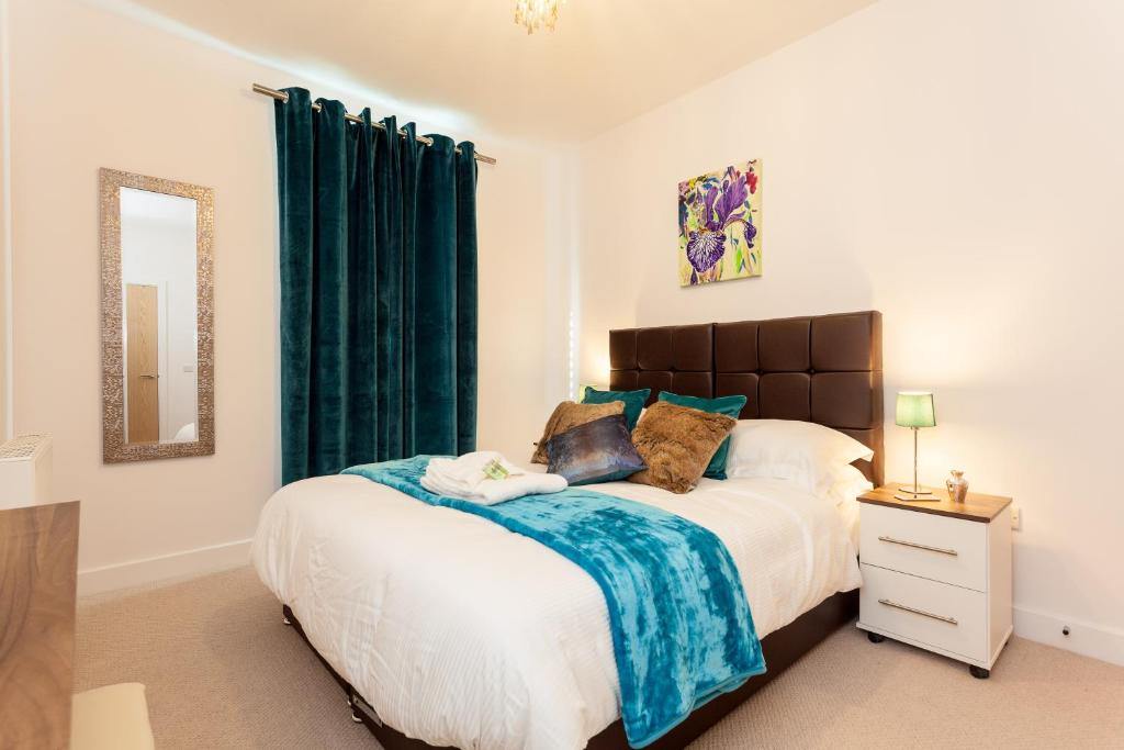 a bedroom with a large bed with green curtains at Self-contained town centre one bedroom apartments by Helmswood Serviced Apartments in Redhill