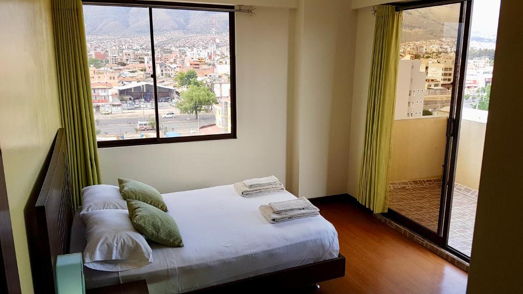 Cama en habitación con ventana grande en C&R apartments, en Cochabamba