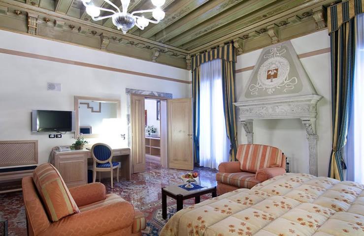 
a hotel room with a bed, chair, table and lamps at Foscari Palace in Venice
