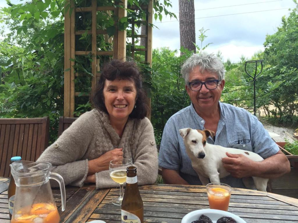 Un uomo e una donna seduti a un tavolo con un cane di Le Relais de la Praya a Lège-Cap-Ferret