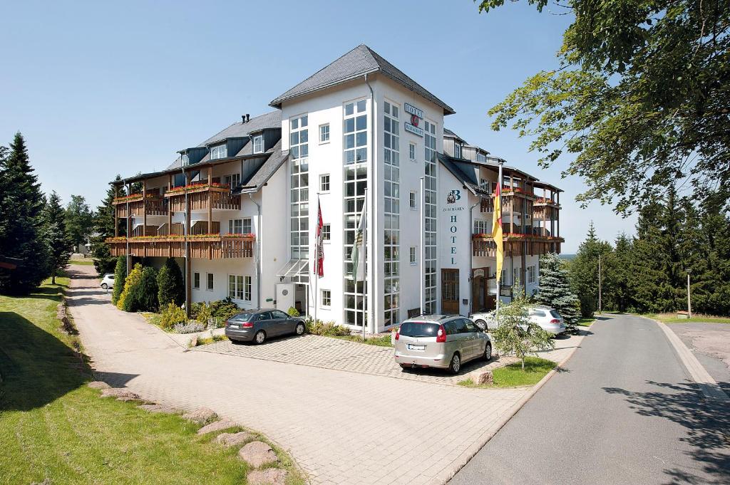 un gran edificio blanco con coches estacionados frente a él en Hotel Zum Bären en Kurort Altenberg