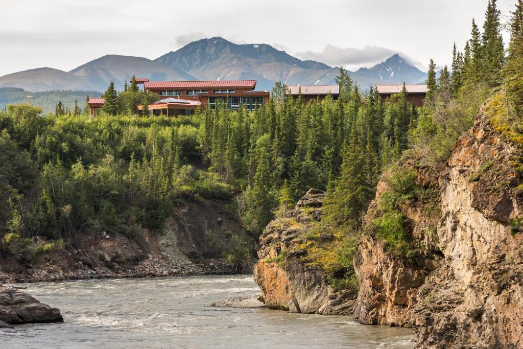 a building on a cliff next to a river at McKinley Chalet Resort in McKinley Park