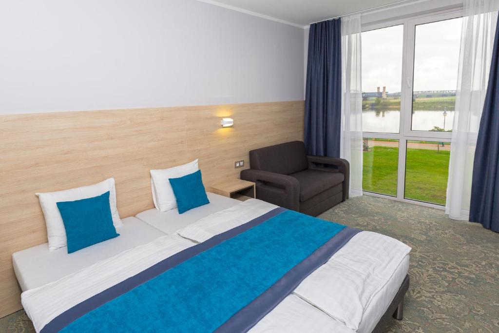 a hotel room with a large bed and a chair at Hotel Vela in Tczew