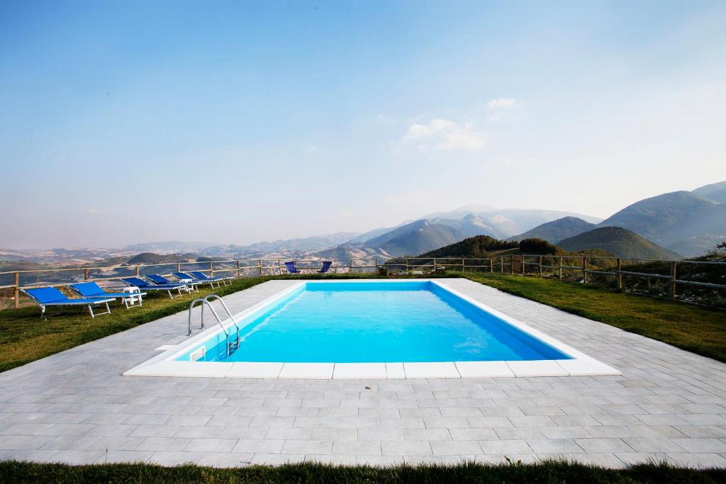 a swimming pool with chairs and mountains in the background at Agriturismo Bufano in Cagli