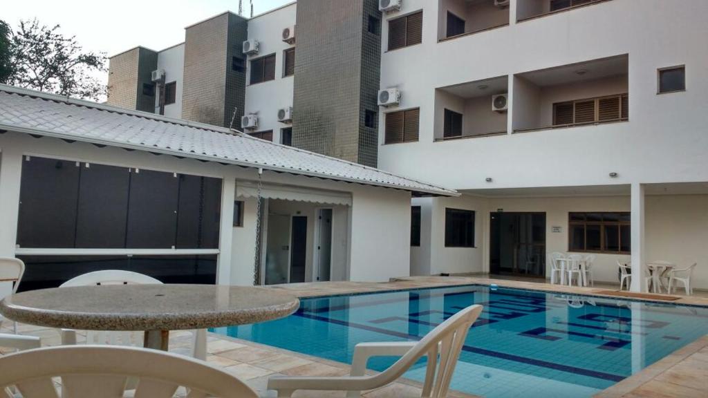 a swimming pool with a table and chairs next to a building at Big Executive Hotel in Araguari