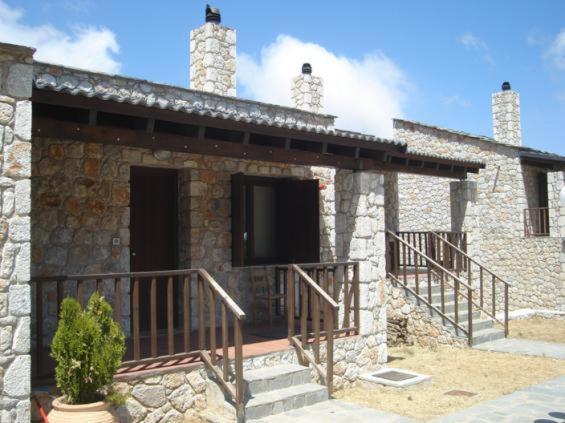 - un bâtiment en pierre avec une terrasse couverte et un balcon dans l'établissement Samaria Village, à Omalós