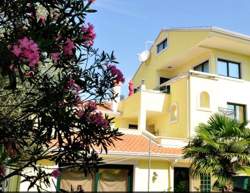 un gran edificio amarillo con flores rosas delante de él en Apartments Adri, Parking in the yard, en Rovinj