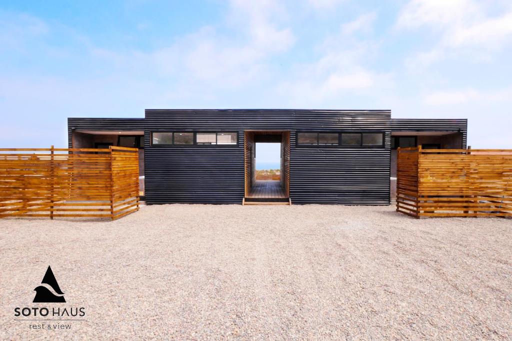 a black house with a wooden fence in front of it at SOTO HAUS Totoralillo Mar in Totoralillo