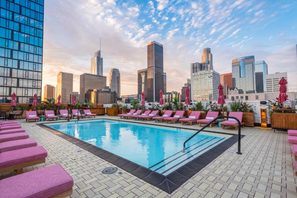 a rooftop pool with pink lounge chairs and a city skyline at Freehand Los Angeles in Los Angeles