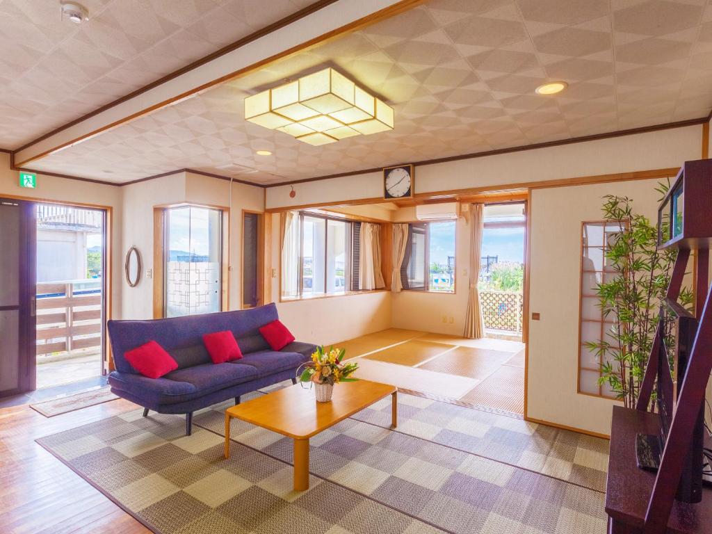 a living room with a blue couch and red pillows at Kariyushi Condominium Resort Sea Side House in Nago