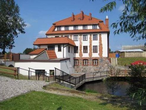 un grand bâtiment avec un pont en face d'une rivière dans l'établissement Pensjonat Bobrowy Dwór, à Szelków Stary