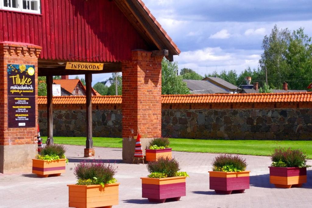 um edifício com um celeiro vermelho com vasos de plantas em Mooste mõisa Linakoja külalistemaja em Mooste