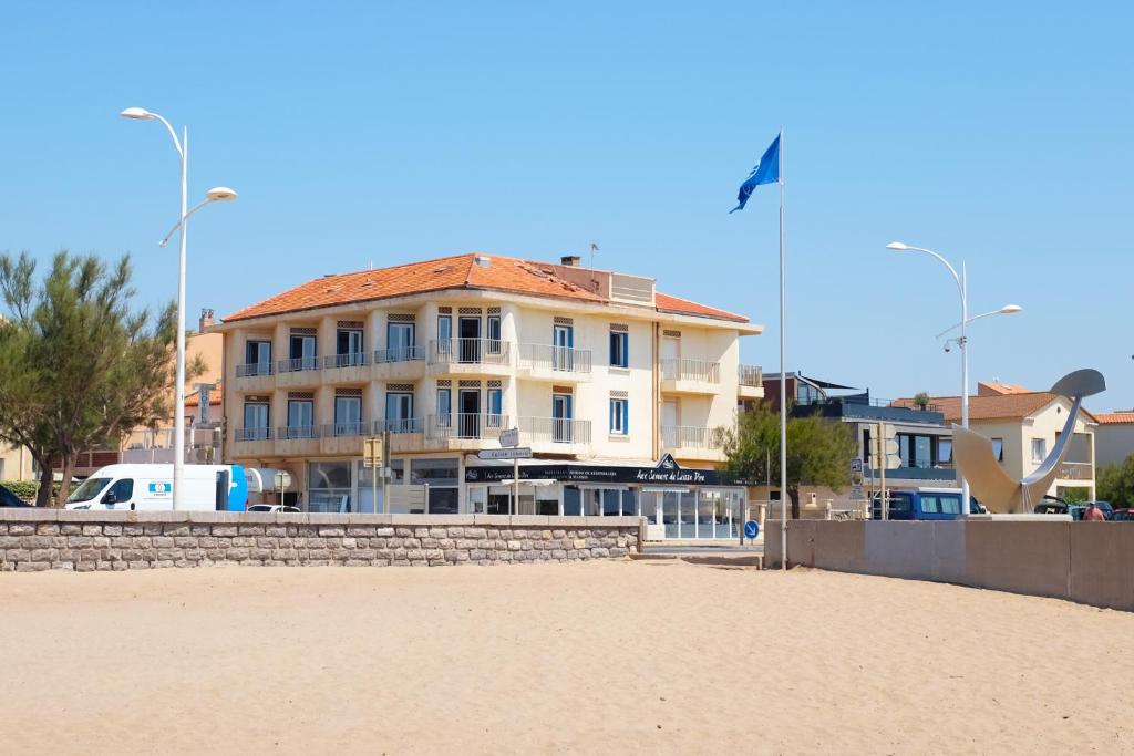 um grande edifício na praia com um edifício em Hôtel de la Mer em Valras-Plage