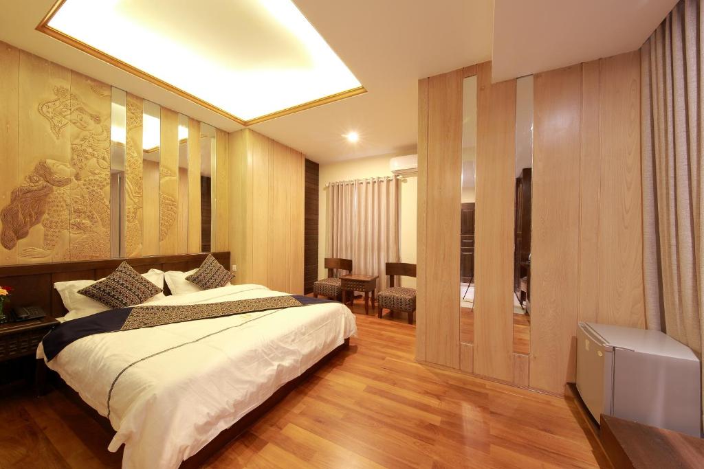 a hotel room with a bed and a television at The Home Hotel in Mandalay