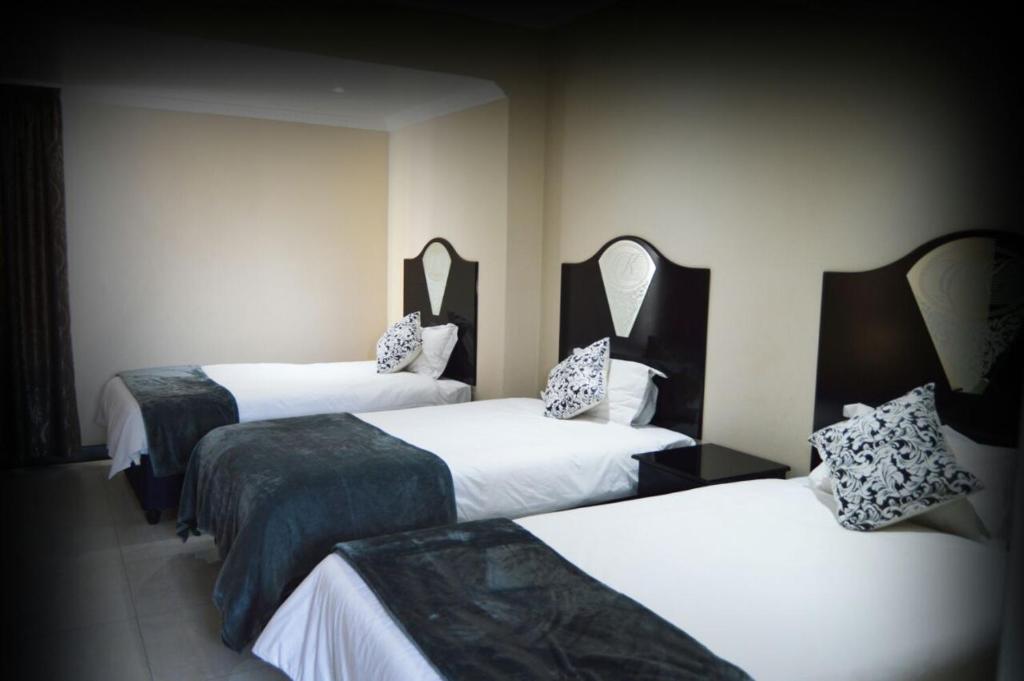 a hotel room with two beds and two mirrors at Kismet Hotel in Pietermaritzburg