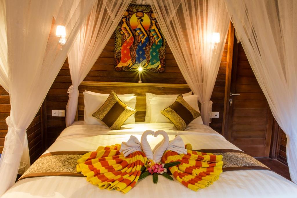 a bedroom with a bed with a bow on it at Seaside Huts Lembongan in Nusa Lembongan