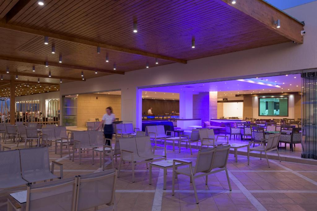 osoba stojąca w pokoju ze stołami i krzesłami w obiekcie Avra Beach Resort w miejscowości Ixiá