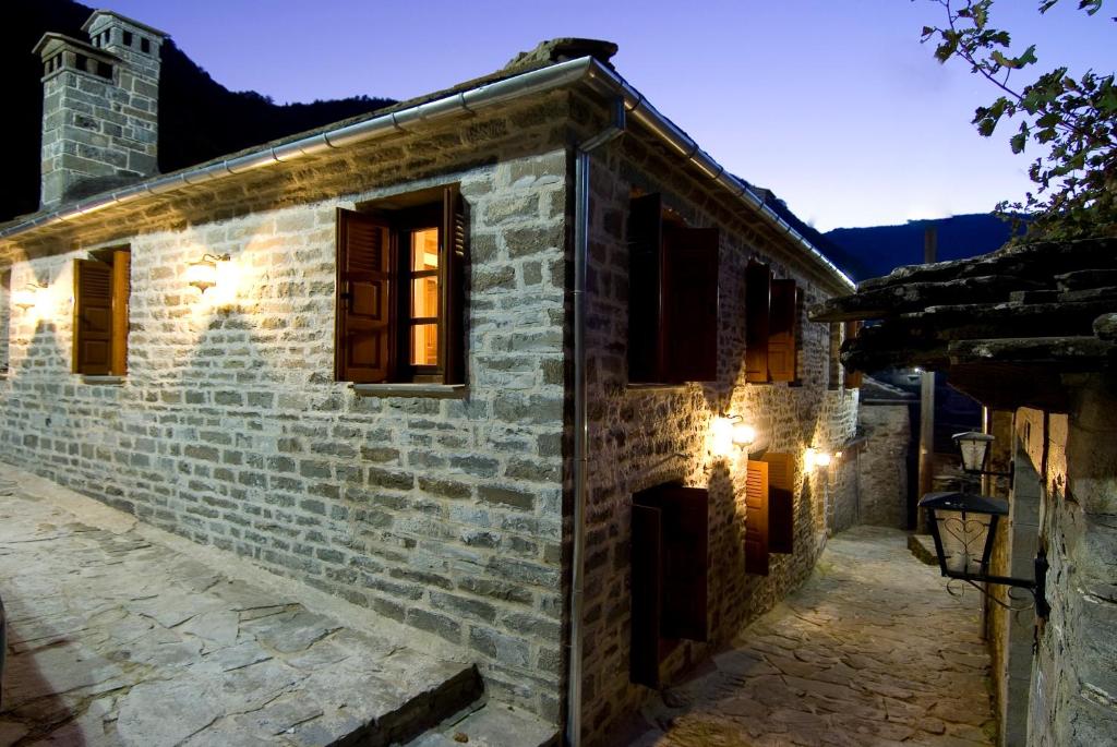 une maison en pierre avec des lumières sur son côté dans l'établissement Kato Machalas, à Dikoryfo