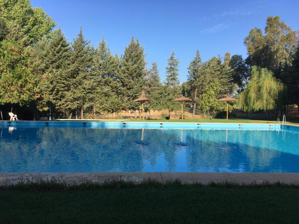 una gran piscina azul con árboles en el fondo en Camping La Fundicion en Cazalla de la Sierra