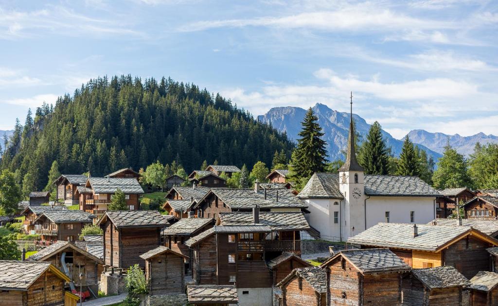 un village avec des maisons et une église dans les montagnes dans l'établissement Hotel Blattnerhof, à Blatten bei Naters