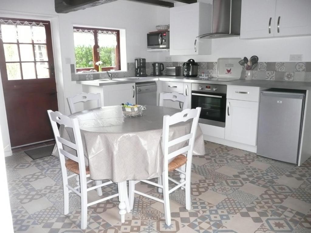 una cucina con tavolo e sedie in una cucina di Rose Cottage En Baie De Somme a Nouvion-en-Ponthieu