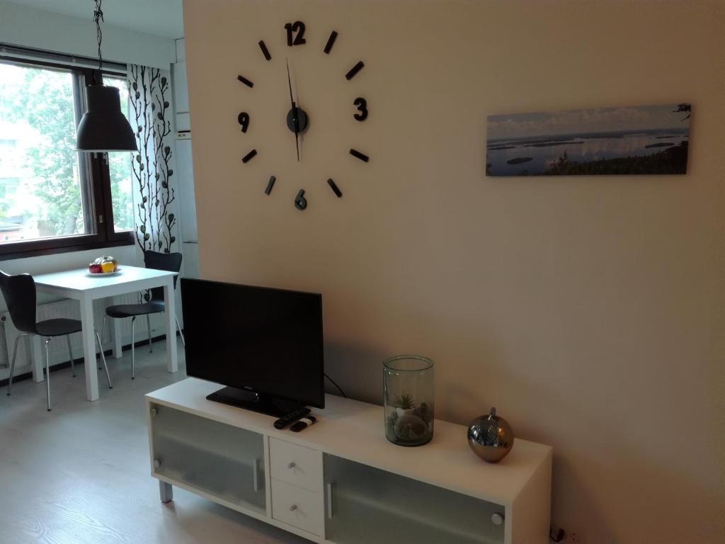 sala de estar con TV y reloj en la pared en A lovely one-room apartment near the city centre., en Vaasa