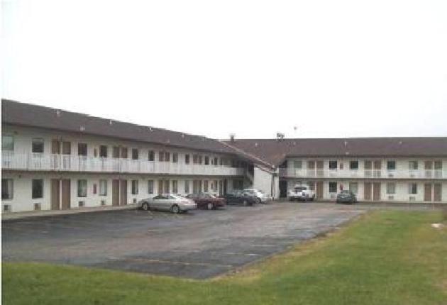 un gran edificio con coches estacionados en un estacionamiento en Hilltop Inn Pittsburgh, en Pittsburgh