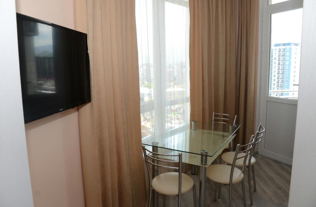 a room with a glass table and chairs and a television at G.M.M Apartaments in Batumi