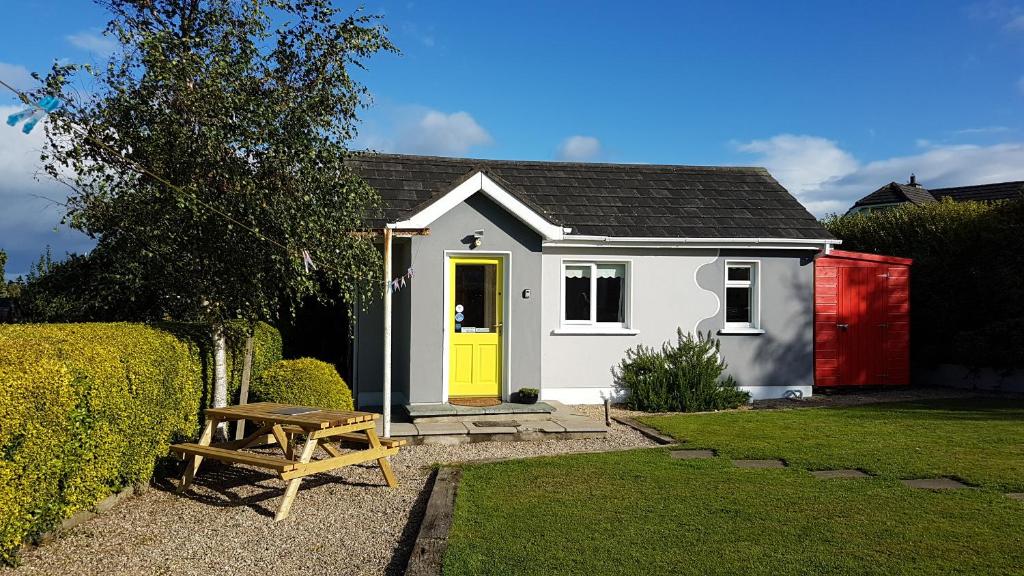 una pequeña casa con una puerta amarilla y una mesa de picnic en Hilltop Seaview Apartment en Wicklow