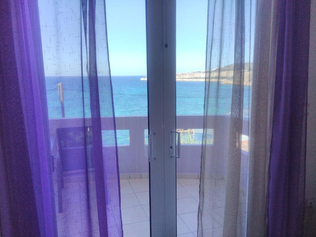 ハニア・タウンにあるAmazing Sea View Apartmentの紫色のカーテンが付いた窓から海の景色を望めます。
