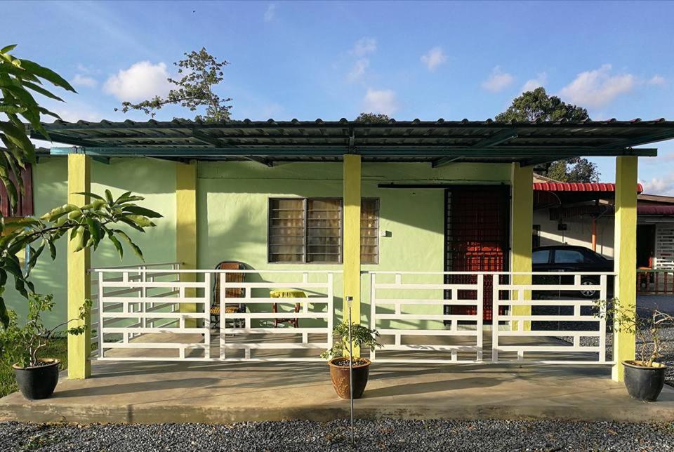 a green house with a white fence in front of it at Chalet Desa Halban in Kangar