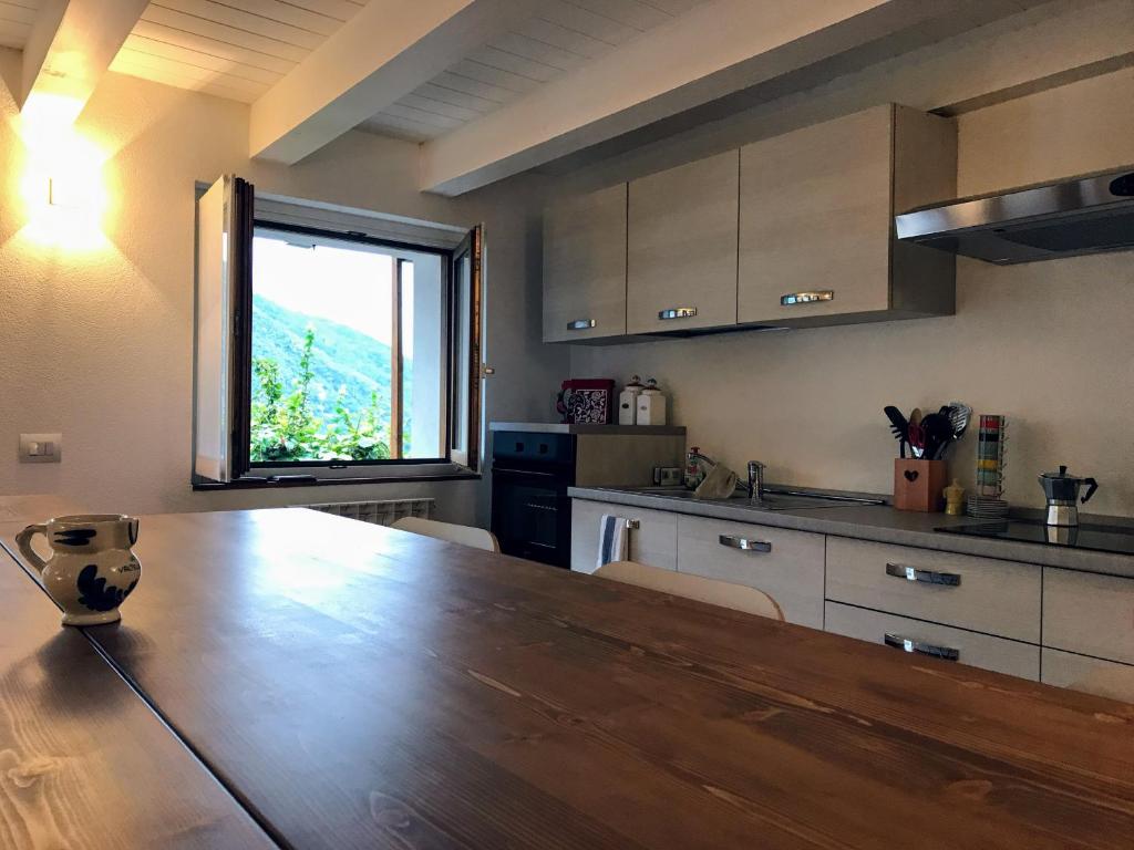 Villa di TiranoにあるCasa Ragnoのキッチン(木製テーブル付)、大きな窓が備わります。
