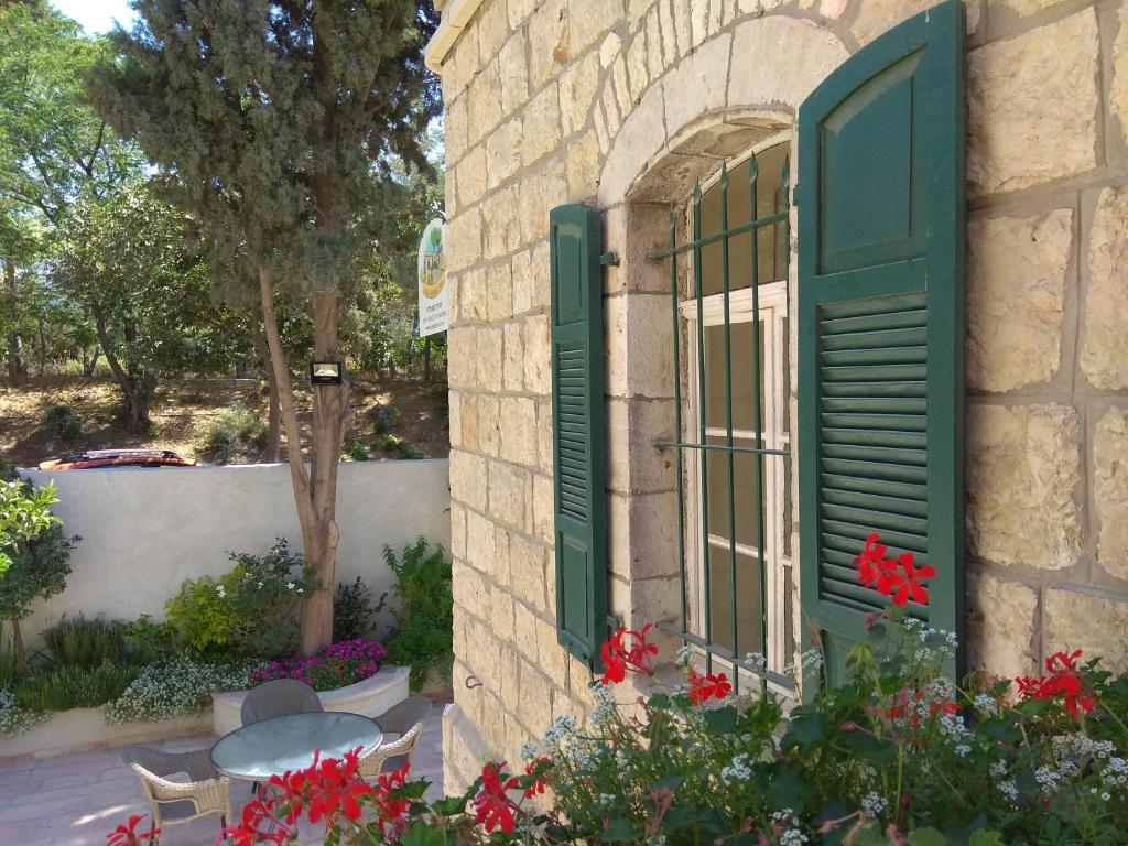 a window with green shutters on a building with flowers at The Templer Inn in Jerusalem