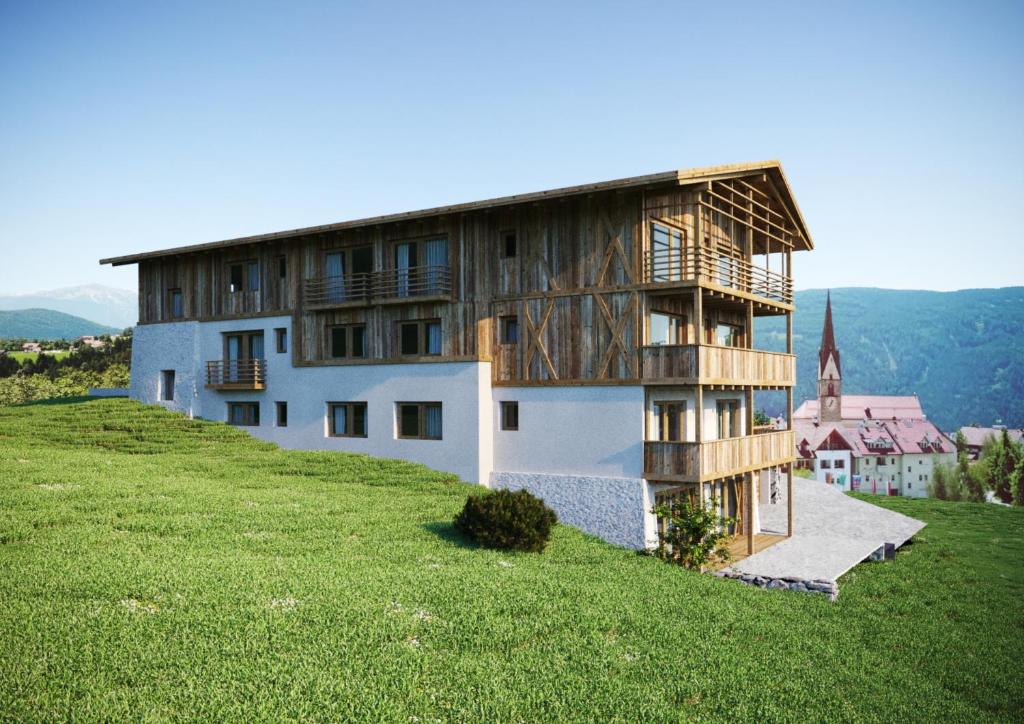 Chalet Schmied في تيرينتو: منزل على قمة تل مع حقل أخضر